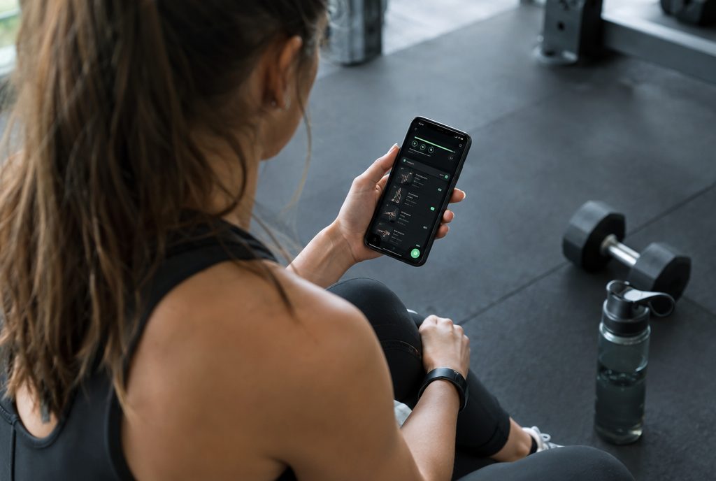 A woman checking her online coaching workout plan on her phone between sets